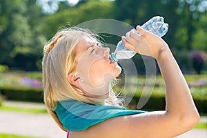 Thirsty young woman finishing water from bottle.
