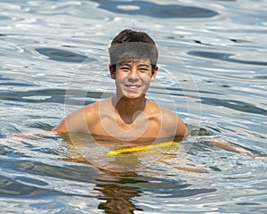 Thirteen year old Amerasian boy smiling as he floats in Grand Lake in the State of Oklahoma