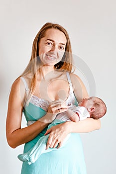 Thirty-year-old mother holds newborn baby in her arms on white background