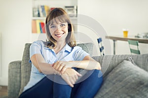 Thirty-year-old natural woman seated in modern home. Looking camera