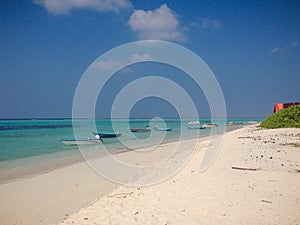 Thoddoo Alif Alif Atoll, Maldives - February 12, 2017: Beautiful sandy beach, motor boats and azure water on the island of