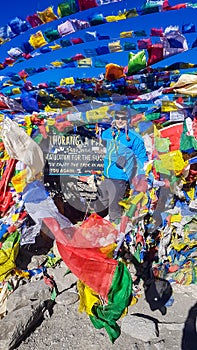 Thorung La Pass - A man standing between the prayer flags on top of the pass