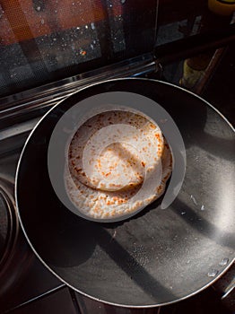 Thosai on non stick pan on gas stove in kitchen with golden hour morning light coming through window