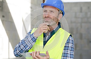 Thoughful engineer writing on writing pad outdoors