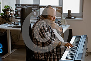 Thoughtfu man with headphones composes music on sound synthesizer in studio photo