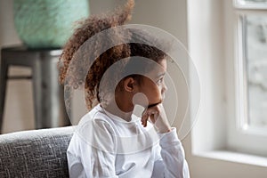 Thoughtful African American preschooler girl looking in window