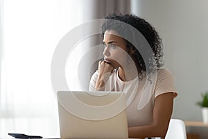 Thoughtful African American woman using laptop, pondering task