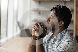 Thoughtful African male employee looks into distance and thinking