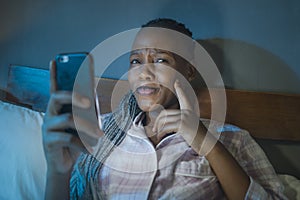 Thoughtful Afro American millennial woman as social media addict - night lifestyle portrait of young beautiful and cool girl