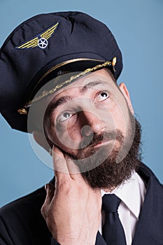 Thoughtful airline pilot in uniform looking upwards, face closeup