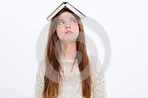 Thoughtful amusing young woman with book on her head