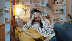 Thoughtful Asia lady suffering from insomnia sit at sofa in living room at house night with feel lonely, Sad depressed teenager