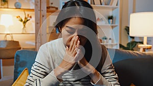 Thoughtful Asia lady suffering from insomnia sit at sofa in living room at house night with feel lonely, Sad depressed teenager