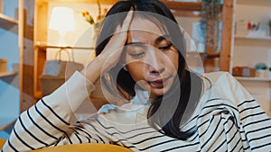 Thoughtful Asia lady suffering from insomnia sit at sofa in living room at house night with feel lonely, Sad depressed teenager