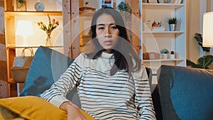 Thoughtful Asia lady suffering from insomnia sit at sofa in living room at house night with feel lonely, Sad depressed teenager