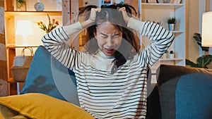 Thoughtful Asia lady suffering from insomnia sit at sofa in living room at house night with feel lonely, Sad depressed teenager