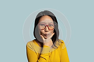 Thoughtful asian woman in eyeglasses look away holding hand on chin.