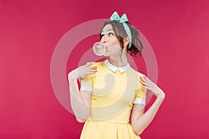 Thoughtful attractive young woman blowing bubble from chewing gum
