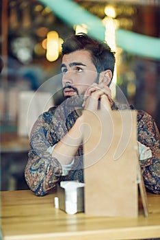 Thoughtful bearded man wearing casual clothes sitting in a moder