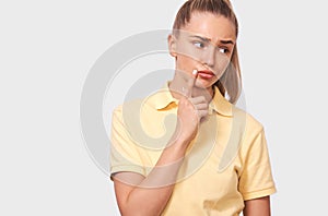 Thoughtful beautiful young woman thinking and looking upwards. confident female, holding finger near the face, looking seriously