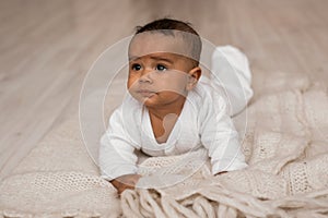 Thoughtful biracial mix of Hispanic and African American infant lying photo