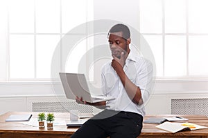 Thoughtful black businessman in casual office, work with laptop
