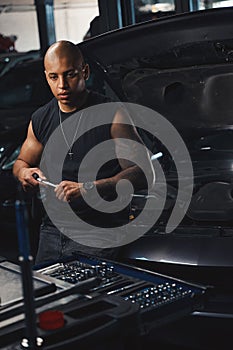 Thoughtful black man auto-mechanic trying to choose special tools and sockets