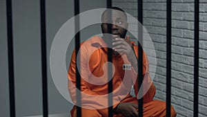 Thoughtful black prisoner sitting in cell, human rights protection, imprisonment