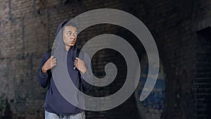 Thoughtful black teen in hoodie with backpack walking dangerous city suburb