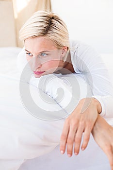 Thoughtful blonde woman lying on the bed