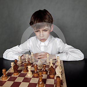 Thoughtful boy playing chess, studio