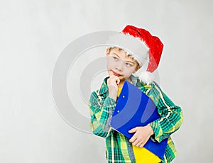 thoughtful boy in a red christmas hat with clipboard