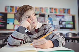 Thoughtful boy studing while sitting at desk