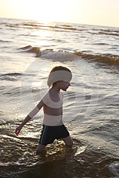 Thoughtful boy walking knee deep in the sea