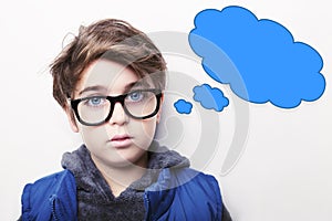 Thoughtful young boy wearing glasses with an empty thought bubble