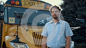 Thoughtful bus driver standing in front yellow vehicle looking camera close up.