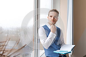 Thoughtful business man with beard in shirt and vest with notepad in his hand