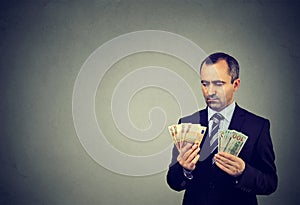 Thoughtful business man looking at euro and dollar cash banknotes