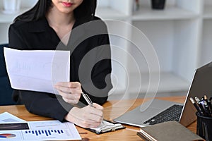 Thoughtful business woman analyzing financial reports while sitting in office.