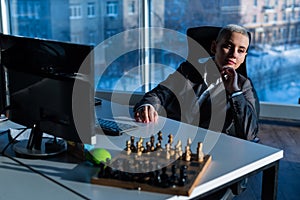Thoughtful business woman sitting at a desk with chess and resting,