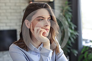 Thoughtful business woman thinking about her problems, looking away, feeling depressed, sitting at table