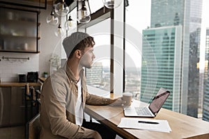 Thoughtful businessman contemplating looks at big city skyscrapers view