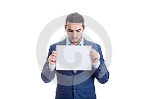 Thoughtful businessman holding a blank paper sheet with copy space, looking down isolated on white background