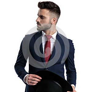 Thoughtful businessman holding his hat and looking to the side