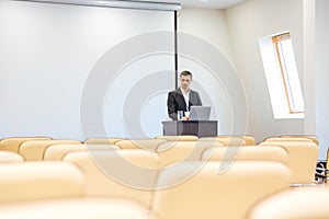 Thoughtful businessman with laptop in empty conference hall