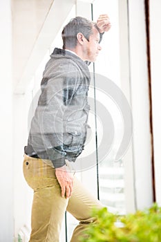 Thoughtful businessman leaning on glass window