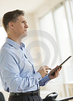 Thoughtful Businessman Looking Away While Holding Digital Tablet