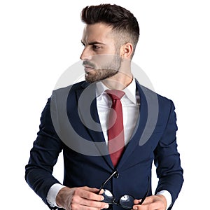 Thoughtful businessman looking to the side and holding his glasses