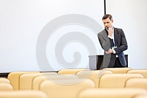 Thoughtful businessman standing in empty conference hall