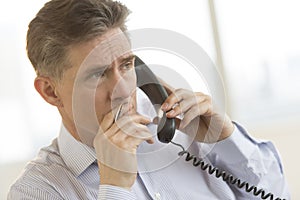 Thoughtful Businessman Using Landline Phone In Office